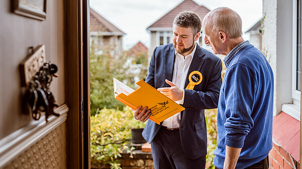 Member talking to gentleman on doorstep with clipboard