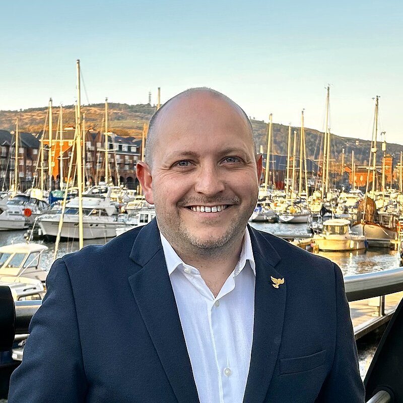 Sam outside South Dock with yachts in background. 