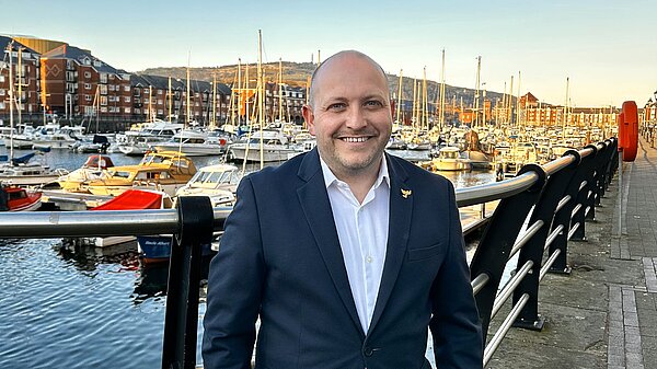 Sam outside South Dock with yachts in background. 