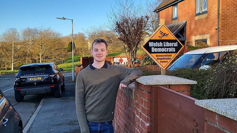 Dan Burton outside house with Welsh Liberal Democrat Garden Poster